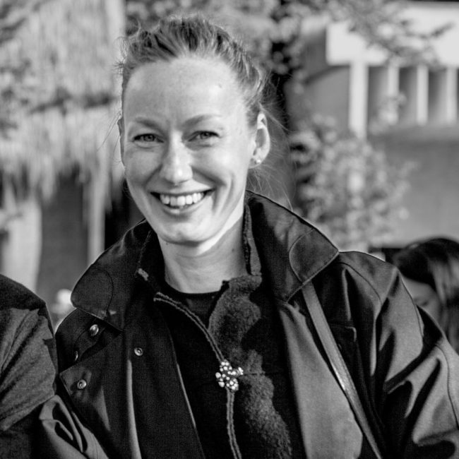 Black and white photo of a woman smiling at the camera.